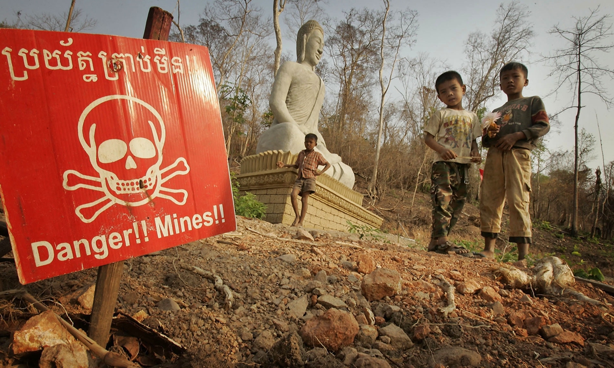 Bambini giocano vicino a un allarme mine antiuomo e a un santuario buddista in Cambogia. Foto: VGC